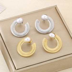 Macro detail of U-shaped gold and silver earrings with stripes and pearl accents