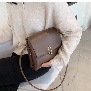 Détail d'un sac à bandoulière minimaliste en cuir marron avec boucle en métal doré