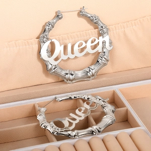 Detail von silbernen Creolen mit Bambustextur und Queen-Schriftzug in der Schmuckbox