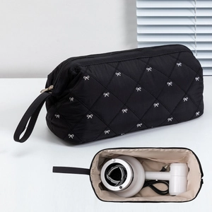 Detail of quilted hair dryer storage bag with bow embroidery showing large inner capacity