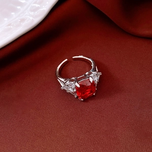 Detail of red square zircon ring with side stones on red velvet background