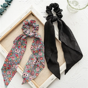 Detail of floral and black ribbon scrunchies placed on a textured artistic background