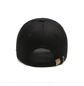Detail of the adjustable bronze metal buckle on a black cotton twill baseball cap