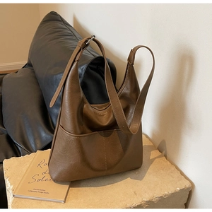 Macro view of textured brown leather hobo bag with adjustable strap on stone base