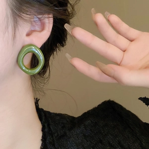 Close-up of model wearing avocado green resin irregular geometric hoop stud earrings