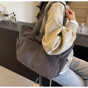 Détail du sac fourre-tout gris en velours côtelé avec texture rayée et poche latérale