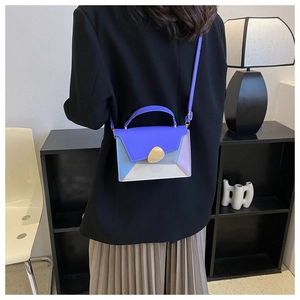 Detailed view of color-block crossbody bag on a model showing leather texture and metal clasp