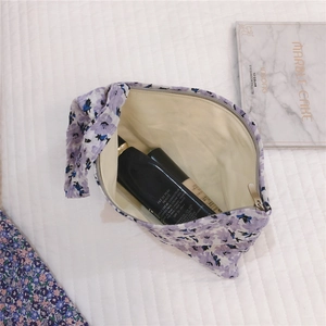 Vue détaillée du sac à cosmétiques à fleurs mauves avec fermeture éclair argentée