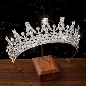Detailed view of silver crystal tiara with intricate scrollwork on black sequin background