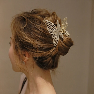 Close-up of a large gold butterfly hair claw clip with white pearls and rhinestones