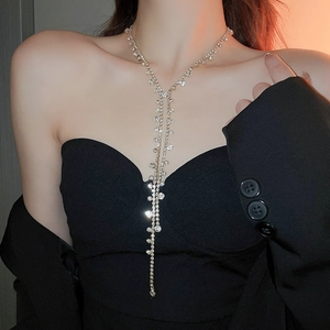 Close-up of sparkling long tassel Y-necklace with rhinestones on a black evening gown