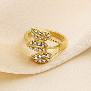 Macro shot of gold-plated hollow leaf ring with white rhinestones on beige silk