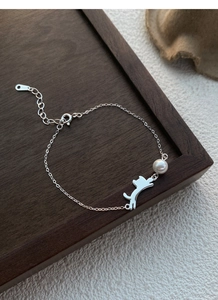 Dettaglio del bracciale gatto e perla in argento S925 su elegante vassoio in legno