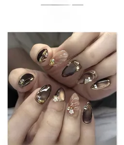 Detalle de uñas almendradas con efecto ojo de gato marrón, bordes 3D y perlas