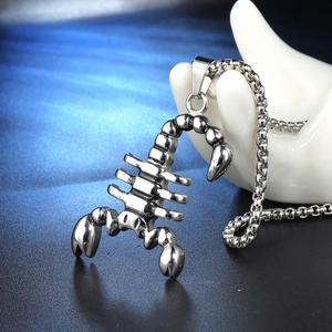 Close-up of silver scorpion pendant with box chain on ceramic hand display