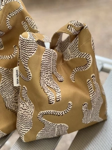 Gros plan du sac fourre-tout en toile jaune avec motif tigre et étiquette tissée