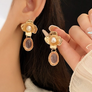 Close-up of vintage gold flower earrings with pearl and pink gemstone on a model