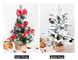 Detail view of two tabletop snow-flocked Christmas trees with red berries and burlap bases