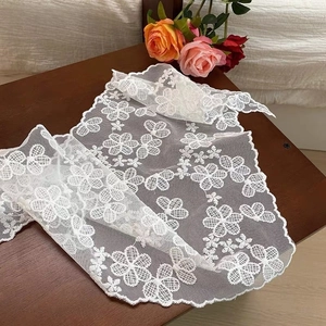 Detailed macro view of white floral embroidery lace with delicate scalloped edges
