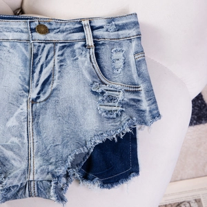 Dettaglio ravvicinato di pantaloncini di denim a vita alta con orli a vivo e patchwork