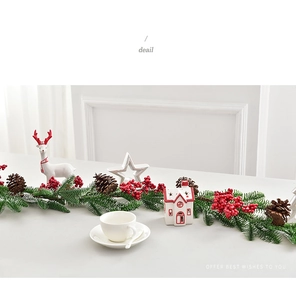 Detail view of a Christmas wreath with green pine needles, red berries, and pine cones