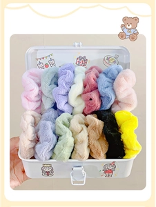 White metal box filled with colorful plush hair scrunchies in various soft pastel colors