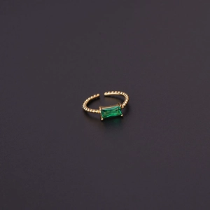 Macro view of gold-plated geometric ring with emerald-cut green zircon and beaded band