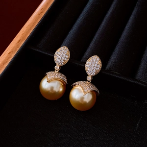 Detail of 18k gold plated leaf earrings with diamonds and large golden pearls