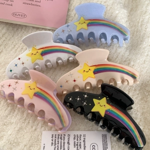 Five-piece star and rainbow hair claw set with rhinestones on soft white fabric background