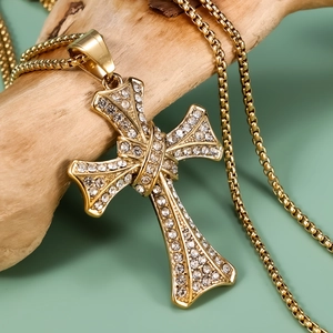 Polished gold cross pendant necklace with white cubic zirconia on a natural wood display