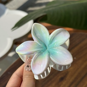 Detailed view of flower-shaped hair claw with pearlescent finish held in hand