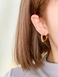Detailansicht von goldenen Herzohrringen mit weißen Zirkonia, von einem Model getragen