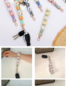 Close-up of handmade woven daisy flower charms with gold metal clasps and keyrings
