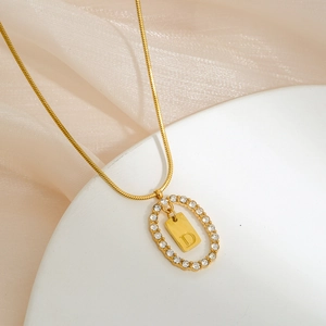 Macro shot of gold D-letter pendant with sparkling crystals on thin snake chain