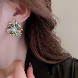 Detail of flower earring with colorful crystals and pearl on model's ear