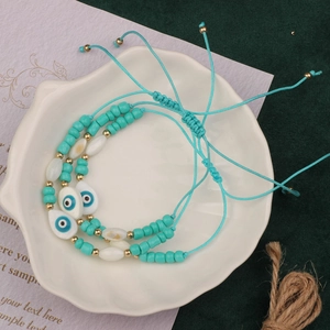 Detail of turquoise beaded bracelet set with devil eye pendant and braided drawstring