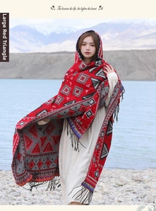 Détail d'un châle tribal rouge à motifs géométriques et franges face aux montagnes