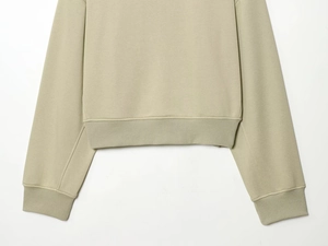 Détail d'un sweat en coton kaki clair montrant l'ourlet et les poignets côtelés