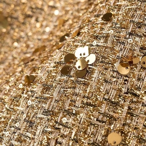 Dettaglio macro del tessuto tweed oro champagne con paillettes e trama ad alta densità