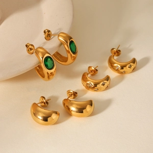 Detailed shot of gold C-shape stainless steel earrings with emerald and zircon inlays
