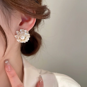 Detailed view of floral pearl cluster earrings worn to show the elegant French chic style