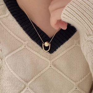 Minimalist 925 sterling silver golden ball pendant necklace on a beige sweater