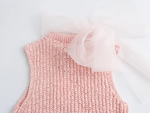 Detail of pink knit top featuring a large white organza bow on the round neckline
