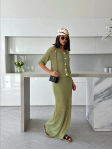 Detail of green crochet knit two-piece set featuring contrast buttons and textured finish