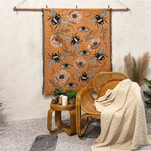 Detail of bohemian tapestry with bee and eye patterns featuring woven fringe edges