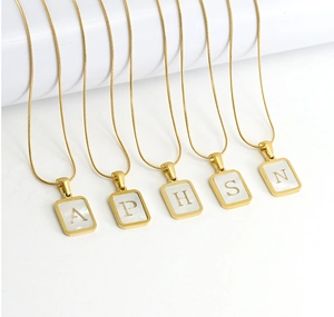 Detail of square white shell pendant necklaces with gold plated hollow alphabet charms