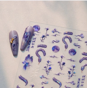 Macro detail of purple laser nail stickers with moon, clouds, and artistic snake motifs
