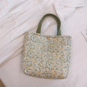 Top view of floral canvas lunch bag with green handles and magnetic bronze clasp