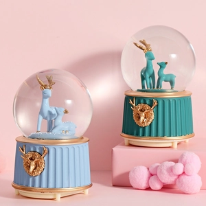 Detail view of crystal ball music box with deer theme on Roman pillar style bases