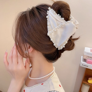 Détail d'une pince à cheveux nœud en soie crème avec perles cousues sur les cheveux